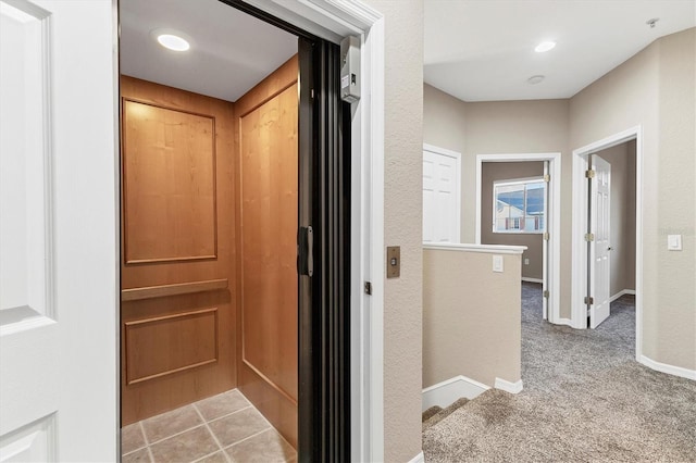 corridor featuring light colored carpet and elevator