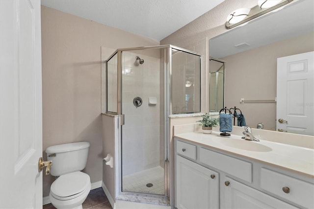 bathroom featuring tile patterned flooring, vanity, a shower with shower door, and toilet