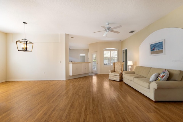 unfurnished living room with a textured ceiling, hardwood / wood-style floors, and ceiling fan with notable chandelier