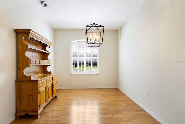 unfurnished dining area featuring light hardwood / wood-style floors and a chandelier