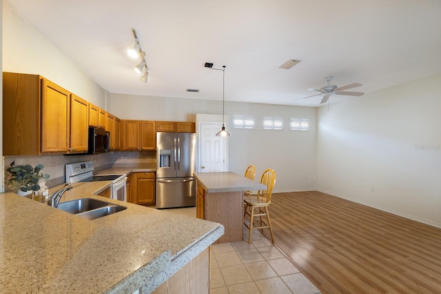 kitchen featuring decorative backsplash, sink, a kitchen island, light wood-type flooring, and appliances with stainless steel finishes