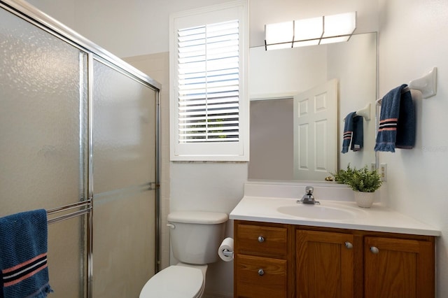 bathroom featuring vanity, toilet, and a shower with shower door