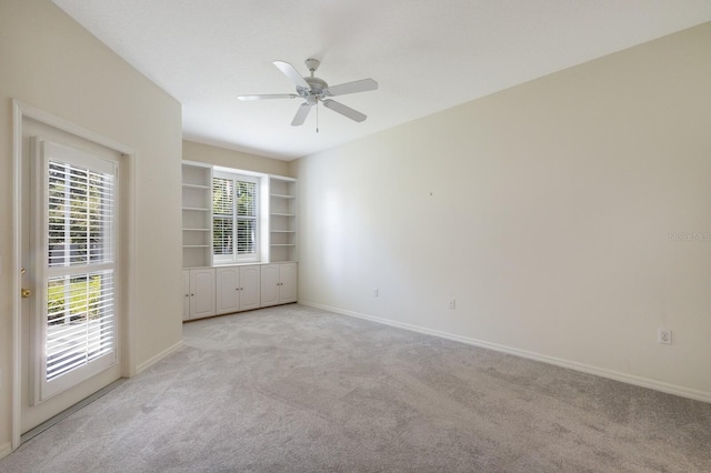 carpeted empty room with built in shelves and ceiling fan