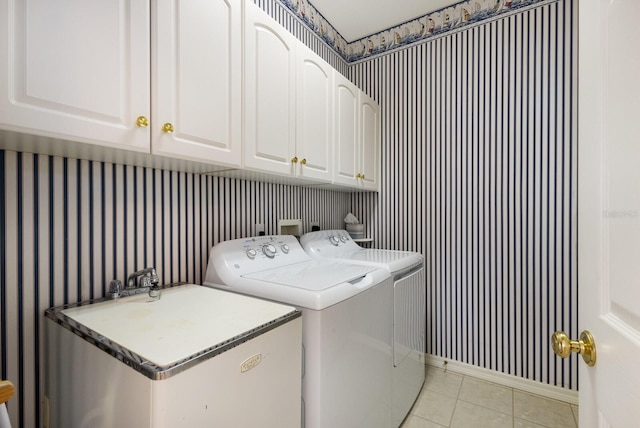 clothes washing area featuring washer and clothes dryer, cabinets, and light tile patterned floors