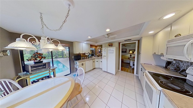 kitchen with white appliances, white cabinets, ceiling fan, a tray ceiling, and light tile patterned flooring