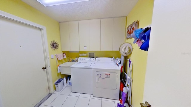 clothes washing area with sink, cabinets, separate washer and dryer, a textured ceiling, and light tile patterned flooring