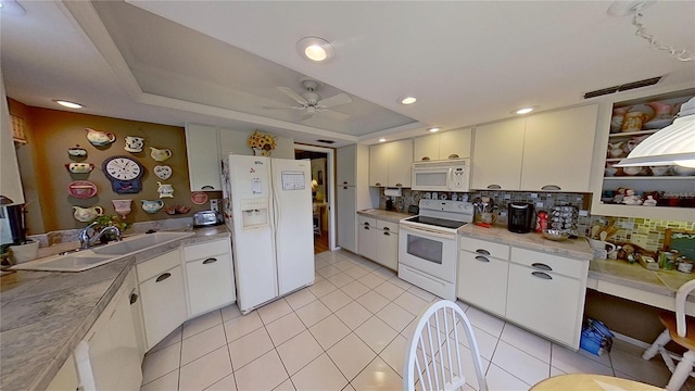 kitchen featuring white appliances, white cabinetry, a raised ceiling, and backsplash