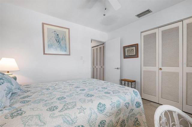 bedroom with two closets, light colored carpet, and ceiling fan