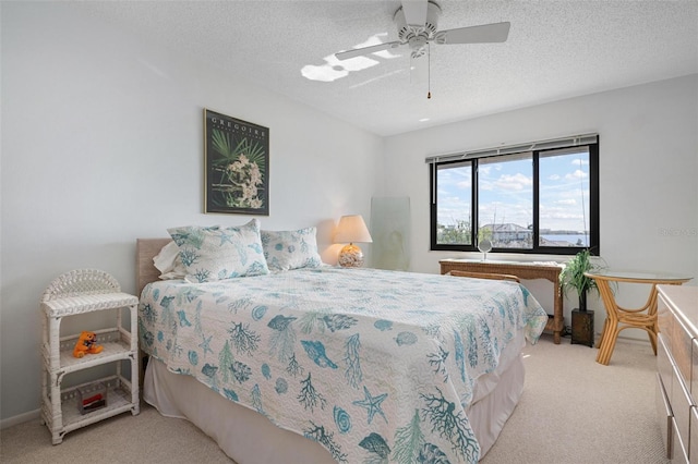 bedroom with ceiling fan, light colored carpet, and a textured ceiling