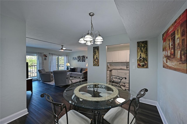 dining area with ceiling fan with notable chandelier, sink, dark hardwood / wood-style floors, and a textured ceiling