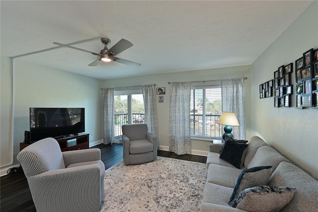 living room featuring ceiling fan, dark wood-type flooring, and a textured ceiling