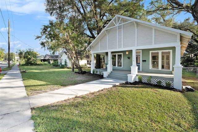 view of front of house featuring a porch, fence, and a front lawn