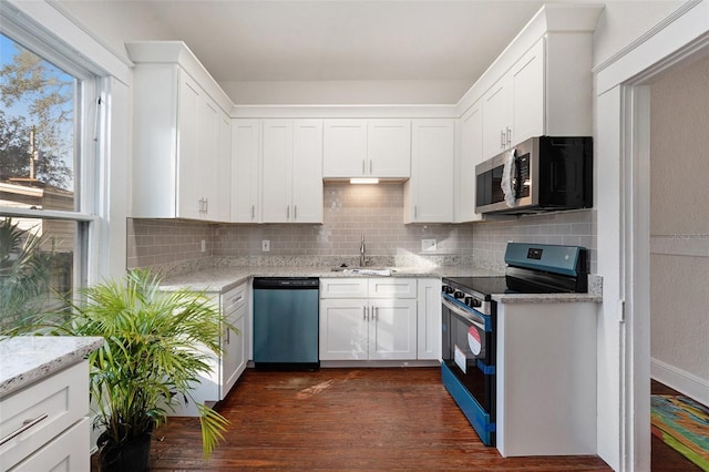 kitchen featuring white cabinetry, backsplash, light stone countertops, stainless steel appliances, and a sink