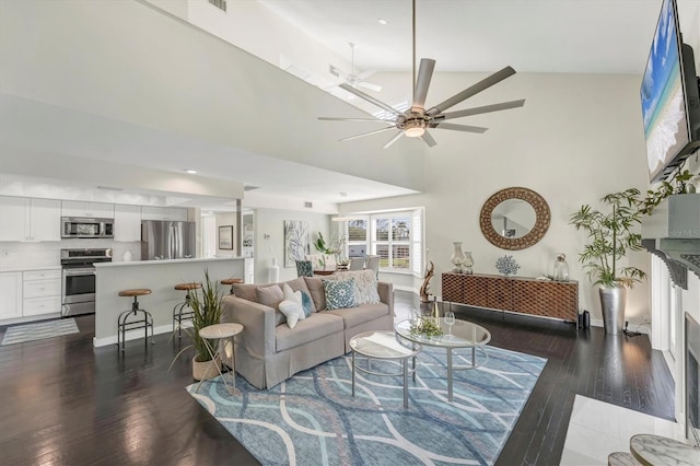 living room with dark hardwood / wood-style flooring, high vaulted ceiling, and ceiling fan