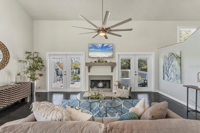 living room with ceiling fan, french doors, a towering ceiling, and dark wood-type flooring