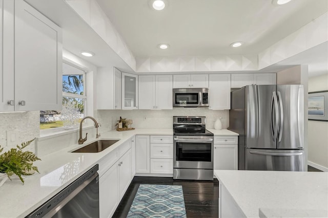 kitchen with dark hardwood / wood-style flooring, tasteful backsplash, stainless steel appliances, sink, and white cabinets