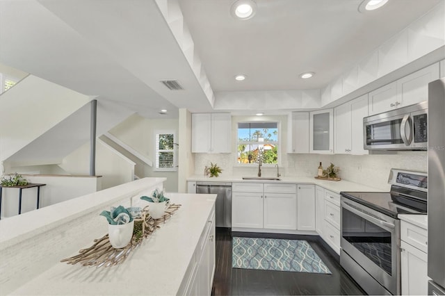 kitchen featuring light stone countertops, stainless steel appliances, sink, white cabinets, and dark hardwood / wood-style floors