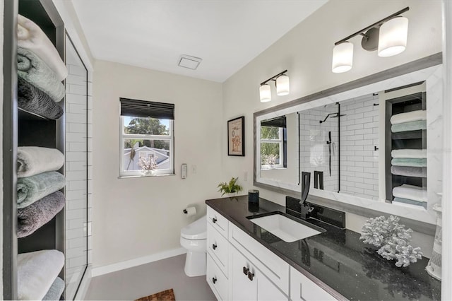 bathroom featuring vanity, a healthy amount of sunlight, a tile shower, and toilet