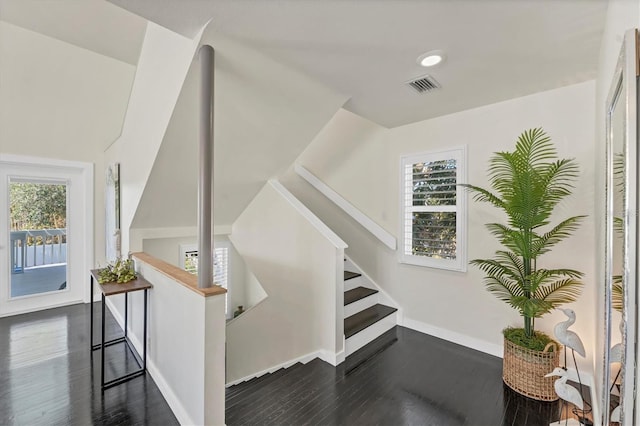 stairs with a wealth of natural light and hardwood / wood-style flooring