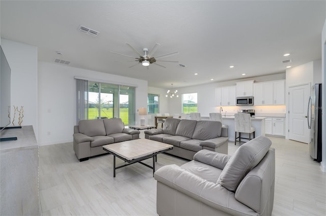 living room featuring ceiling fan with notable chandelier