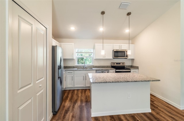 kitchen with white cabinets, appliances with stainless steel finishes, and decorative light fixtures