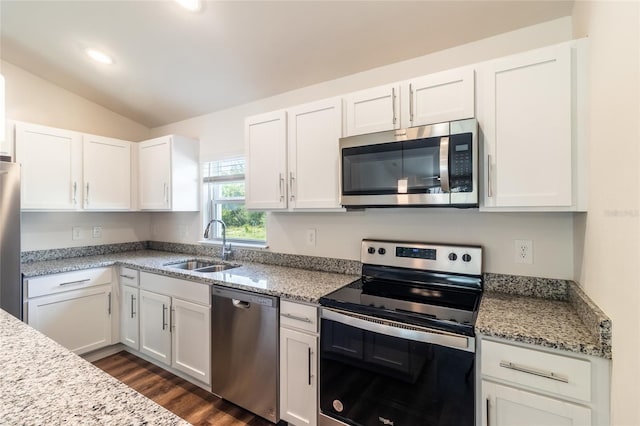 kitchen with stainless steel appliances, white cabinetry, light stone countertops, lofted ceiling, and dark wood-type flooring