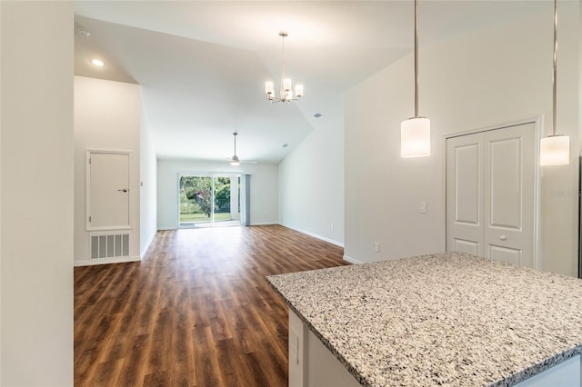 interior space with ceiling fan with notable chandelier, dark wood-type flooring, decorative light fixtures, and light stone counters