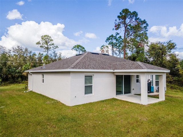 back of property with a lawn and a patio