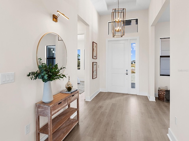 foyer with light hardwood / wood-style flooring, a high ceiling, and an inviting chandelier