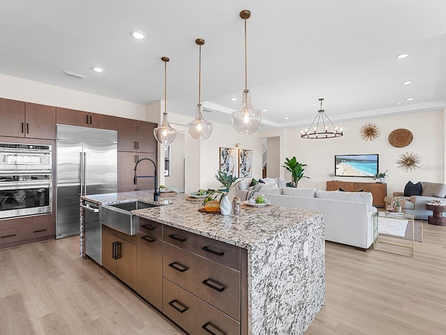 kitchen with stainless steel appliances, a kitchen island with sink, and light hardwood / wood-style floors