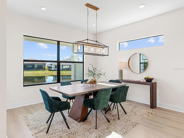 dining space with light hardwood / wood-style floors and a water view