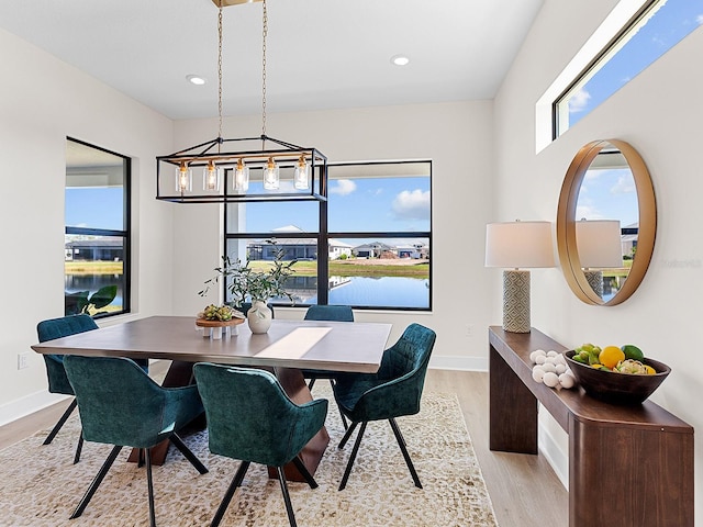 dining space featuring a notable chandelier, a water view, and light wood-type flooring