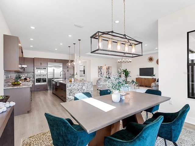 dining area featuring crown molding, sink, and light hardwood / wood-style floors