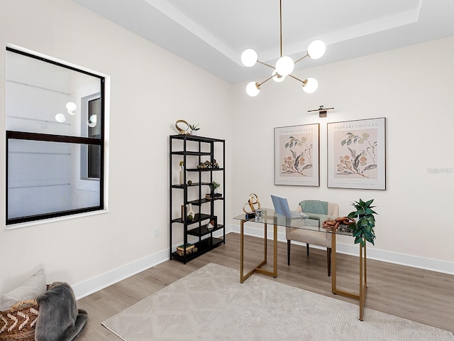 home office with wood-type flooring, a tray ceiling, and an inviting chandelier