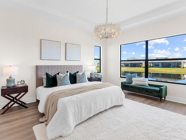 bedroom featuring wood-type flooring, a water view, and a notable chandelier