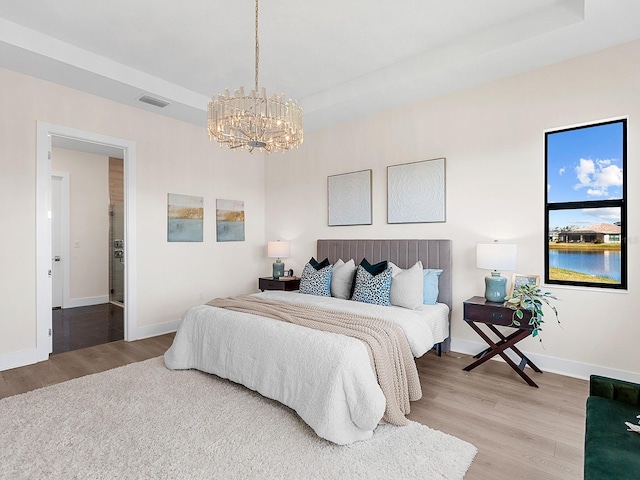 bedroom with ensuite bathroom, a chandelier, and hardwood / wood-style flooring