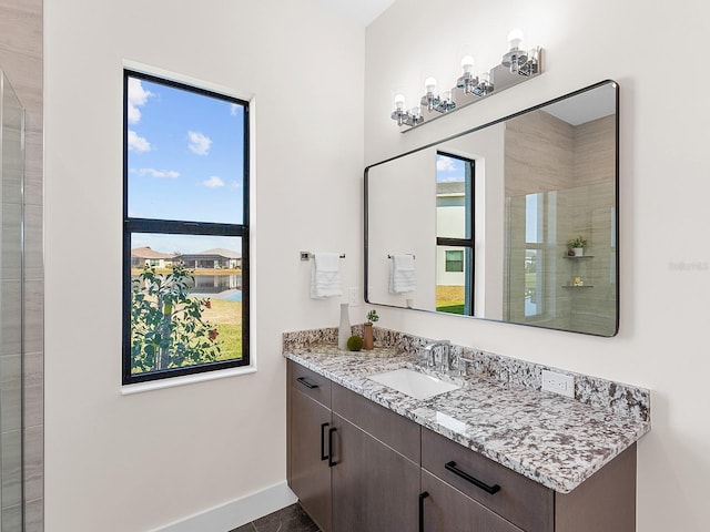 bathroom with vanity, a shower with door, and a healthy amount of sunlight