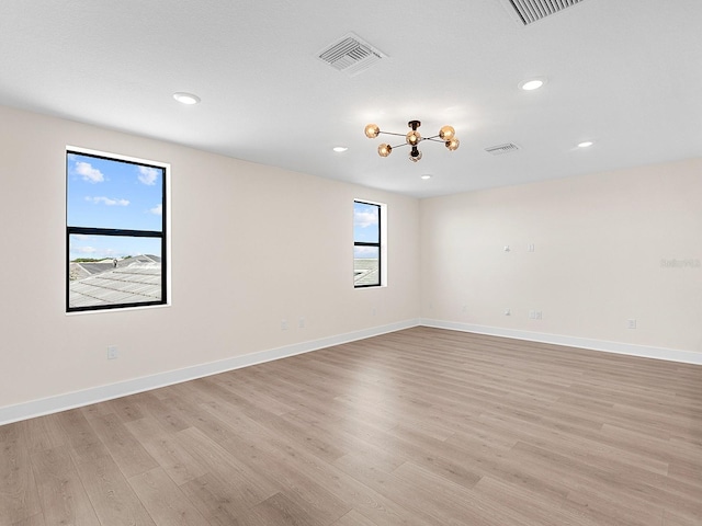 empty room with a chandelier and light hardwood / wood-style flooring