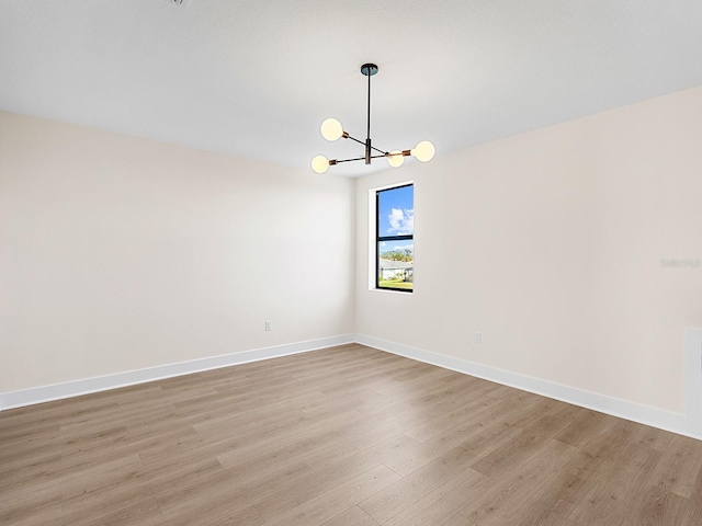 unfurnished room with a chandelier and light hardwood / wood-style flooring