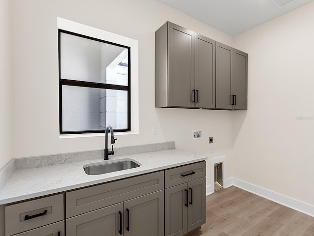 clothes washing area with cabinets, hookup for a washing machine, light wood-type flooring, electric dryer hookup, and sink