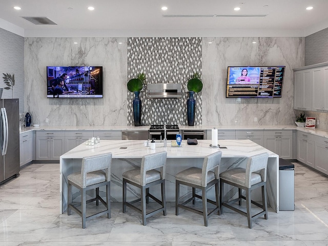 bar with gray cabinetry, light stone counters, sink, and stainless steel appliances