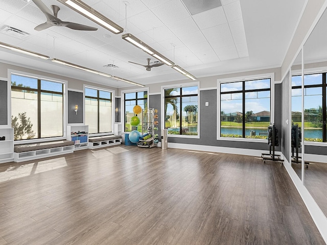 exercise room with hardwood / wood-style flooring, ceiling fan, and a water view