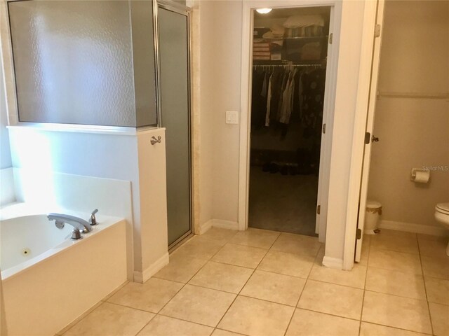 bathroom featuring tile patterned flooring, toilet, and plus walk in shower