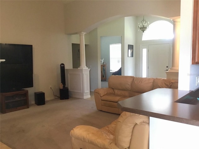 living room featuring light colored carpet, decorative columns, and a chandelier