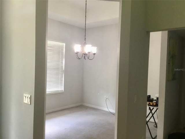 carpeted spare room with a notable chandelier