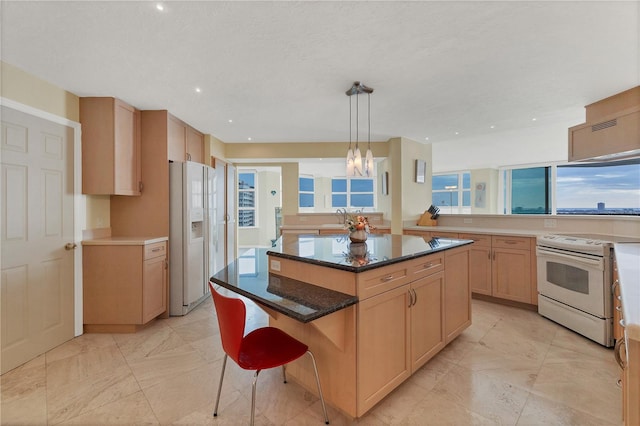 kitchen featuring a kitchen breakfast bar, dark stone counters, white appliances, pendant lighting, and a kitchen island