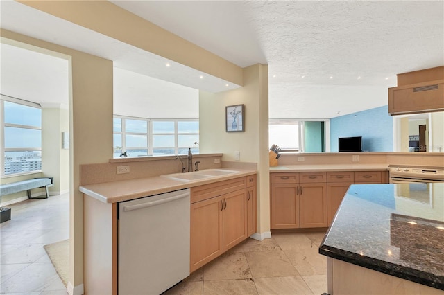 kitchen with sink, light stone counters, kitchen peninsula, a textured ceiling, and white appliances