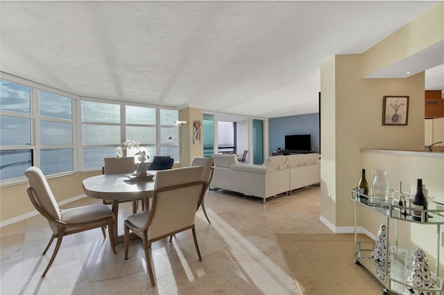 tiled dining area with a textured ceiling and a wall of windows