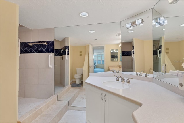 bathroom with vanity, tile patterned flooring, toilet, a textured ceiling, and a tile shower