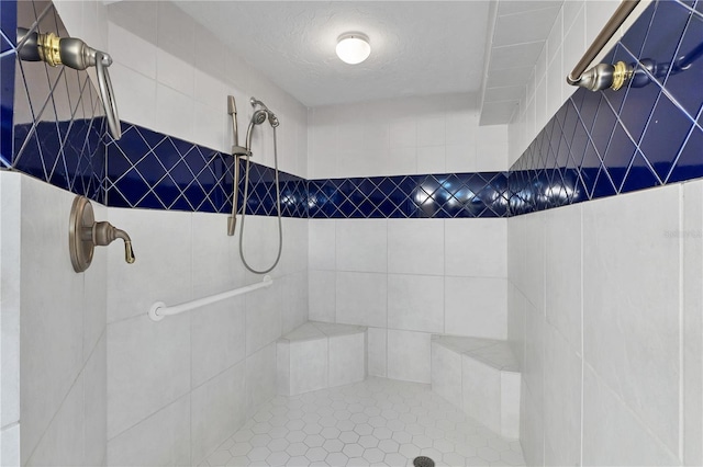 bathroom featuring a tile shower, a textured ceiling, and tile walls